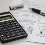 Calculatrice et stylo sur feuille de calcul avec écriture manuscrite